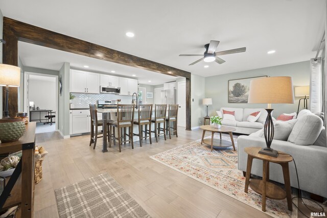 living area featuring a ceiling fan, beamed ceiling, recessed lighting, and light wood finished floors