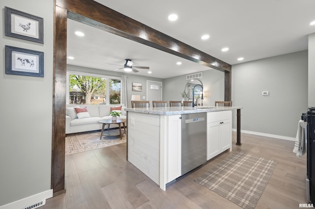 kitchen featuring visible vents, wood finished floors, dishwasher, white cabinets, and open floor plan