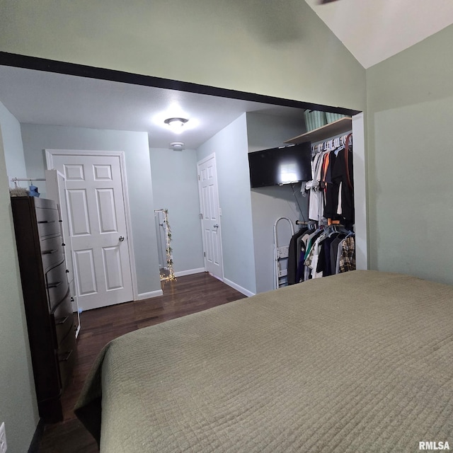 bedroom with baseboards, lofted ceiling, and wood finished floors