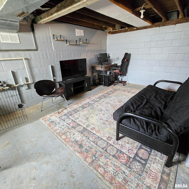 living area with unfinished concrete floors, concrete block wall, and visible vents