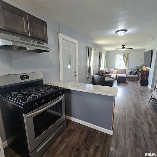 kitchen with a peninsula, stainless steel gas stove, dark wood-type flooring, light countertops, and under cabinet range hood
