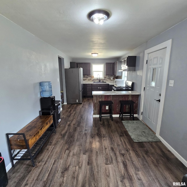 kitchen with dark wood finished floors, light countertops, gas stove, freestanding refrigerator, and a peninsula