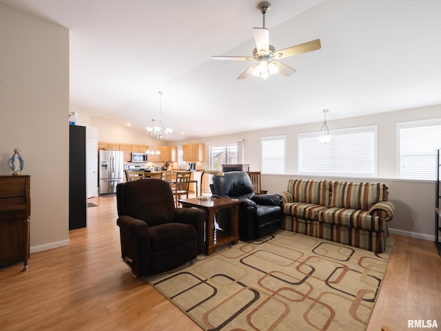 living area featuring light wood finished floors, lofted ceiling, ceiling fan with notable chandelier, and baseboards