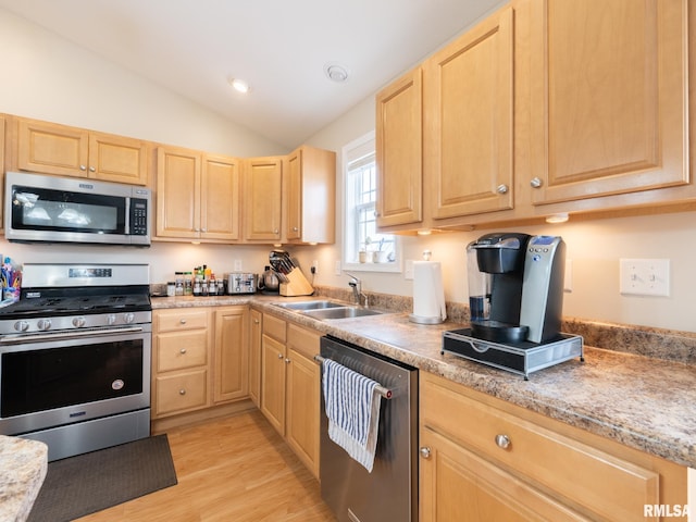 kitchen with appliances with stainless steel finishes, light brown cabinets, a sink, and light wood-type flooring