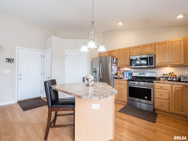 kitchen with a center island, a kitchen breakfast bar, light brown cabinets, light wood-type flooring, and appliances with stainless steel finishes