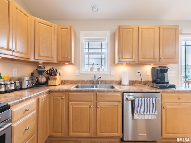 kitchen with light brown cabinets, a toaster, stainless steel dishwasher, a sink, and light countertops