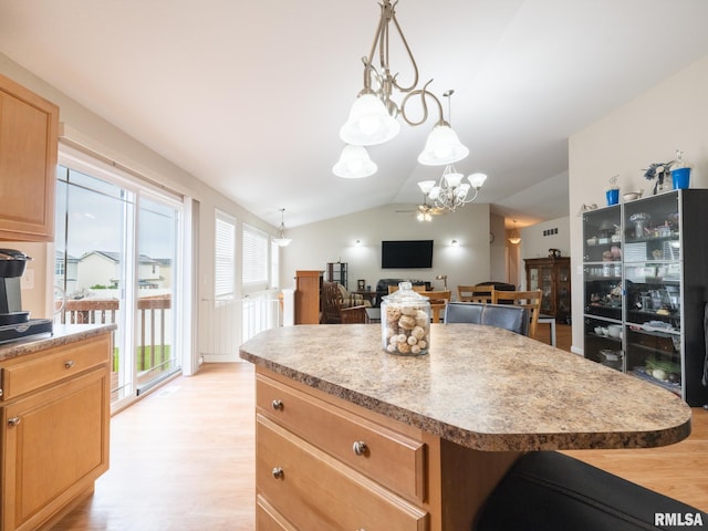 kitchen with vaulted ceiling, a notable chandelier, light brown cabinets, a kitchen island, and light wood-style floors
