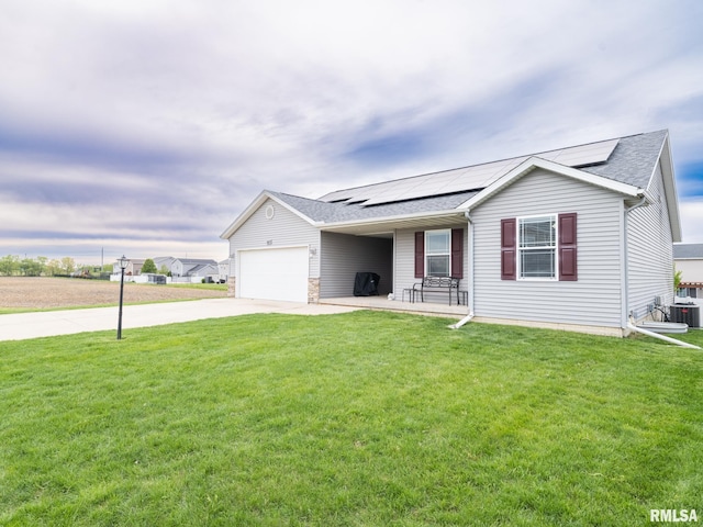 ranch-style house featuring roof mounted solar panels, a garage, concrete driveway, central AC unit, and a front yard