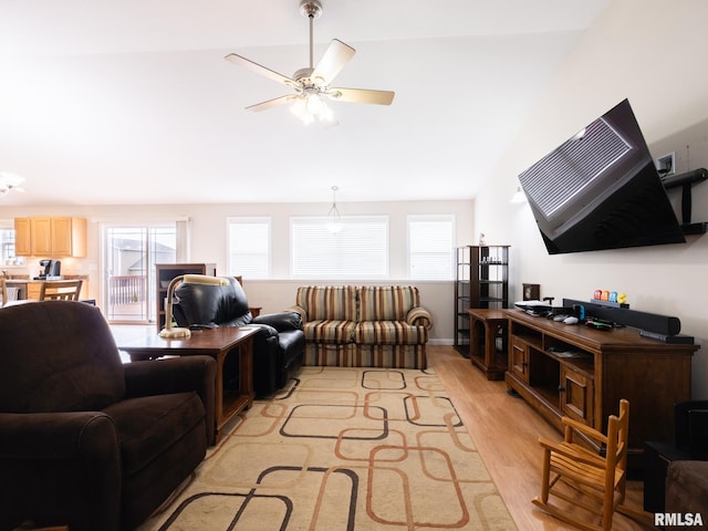living room featuring vaulted ceiling, light wood-style flooring, and a ceiling fan