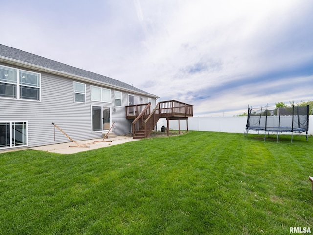 back of house with a lawn, fence, stairs, a trampoline, and a deck