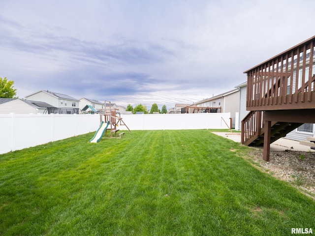 view of yard with a fenced backyard, a residential view, stairway, a wooden deck, and a playground