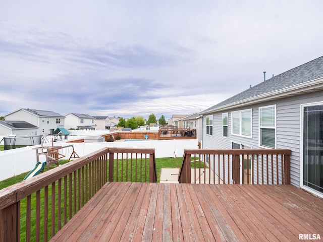 deck featuring a playground, a residential view, a lawn, and a fenced backyard