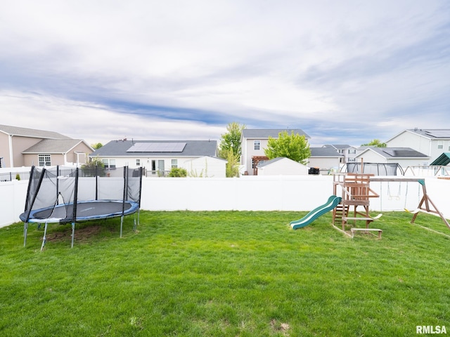 view of yard featuring a playground, a trampoline, a residential view, and a fenced backyard