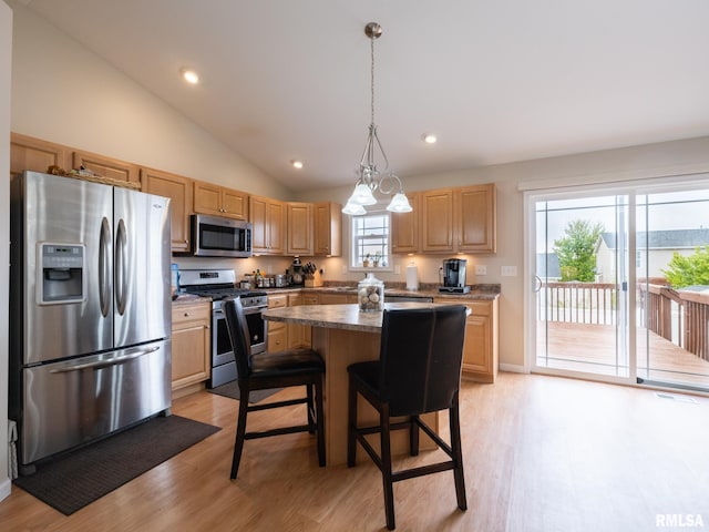 kitchen featuring lofted ceiling, stainless steel appliances, light wood-type flooring, a center island, and light brown cabinets