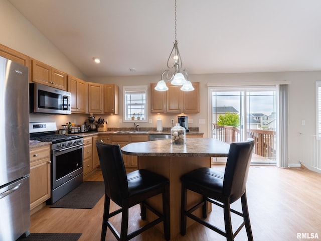 kitchen featuring a sink, light wood finished floors, stainless steel appliances, and light brown cabinetry