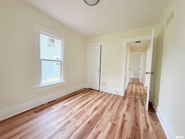 unfurnished bedroom with light wood-style floors, multiple windows, and visible vents