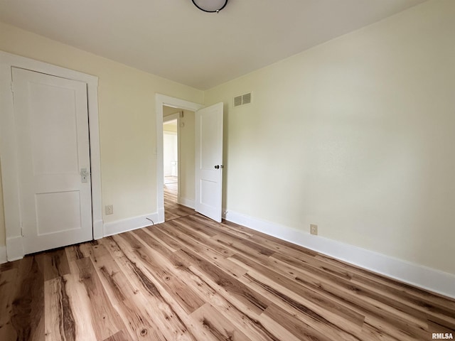 unfurnished bedroom with baseboards, wood finished floors, and visible vents