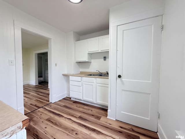 kitchen featuring baseboards, light wood-style flooring, white cabinetry, and light countertops