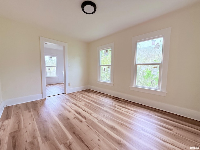 unfurnished room featuring light wood-style floors, baseboards, and a wealth of natural light