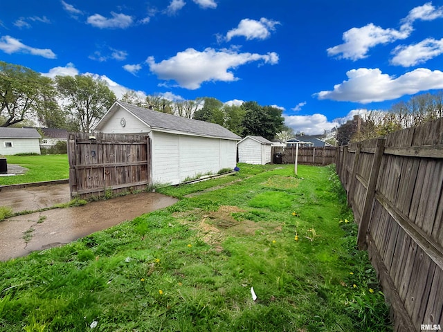 view of yard with an outdoor structure, a fenced backyard, and a shed