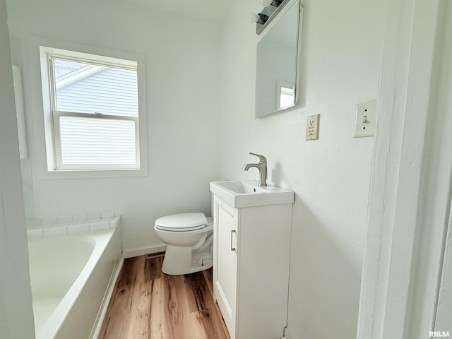 full bathroom featuring vanity, a bathing tub, wood finished floors, and toilet