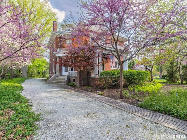 view of front of property with brick siding, driveway, and a chimney