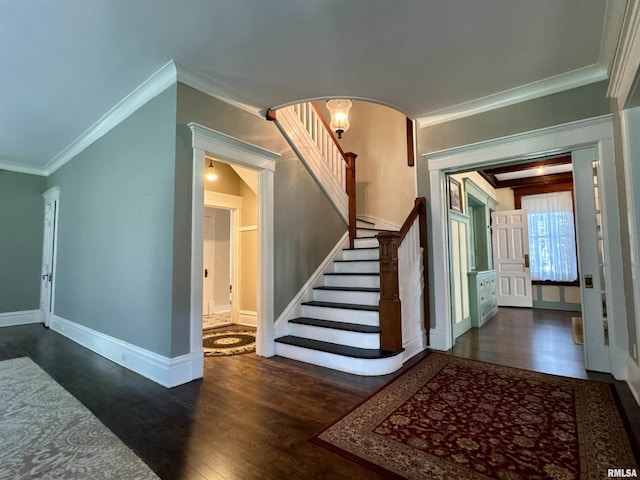 entrance foyer with ornamental molding, stairs, baseboards, arched walkways, and dark wood finished floors