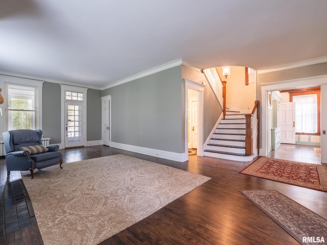living room featuring crown molding, baseboards, wood finished floors, and stairway