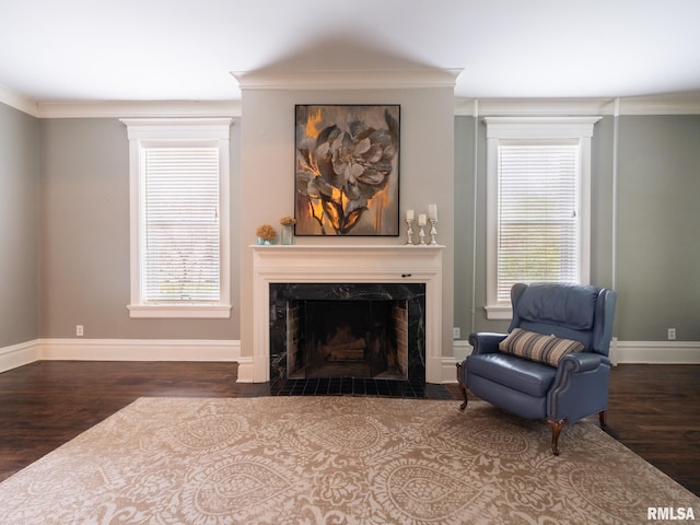 sitting room featuring a high end fireplace, baseboards, crown molding, and wood finished floors