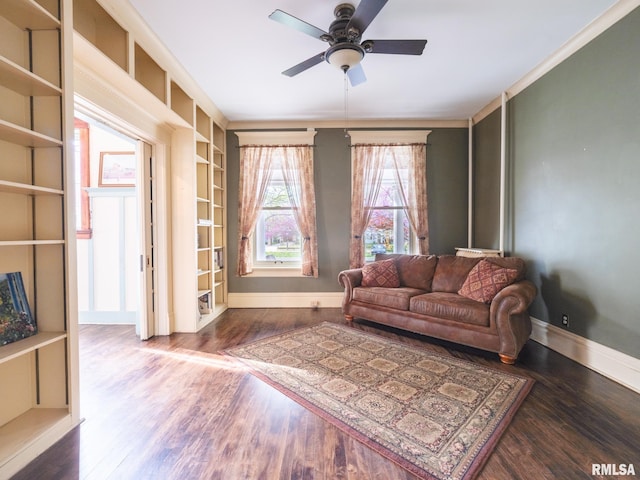 living area featuring built in shelves, baseboards, a ceiling fan, and wood finished floors