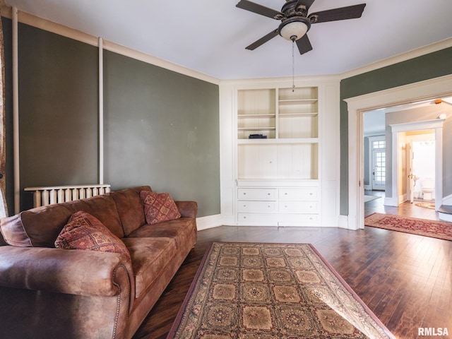living room featuring built in features, baseboards, wood-type flooring, and a ceiling fan