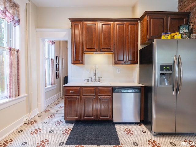 kitchen featuring light countertops, stainless steel appliances, a wealth of natural light, and a sink