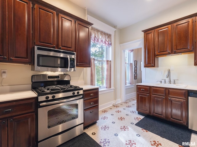 kitchen featuring light countertops, a sink, baseboards, and stainless steel appliances