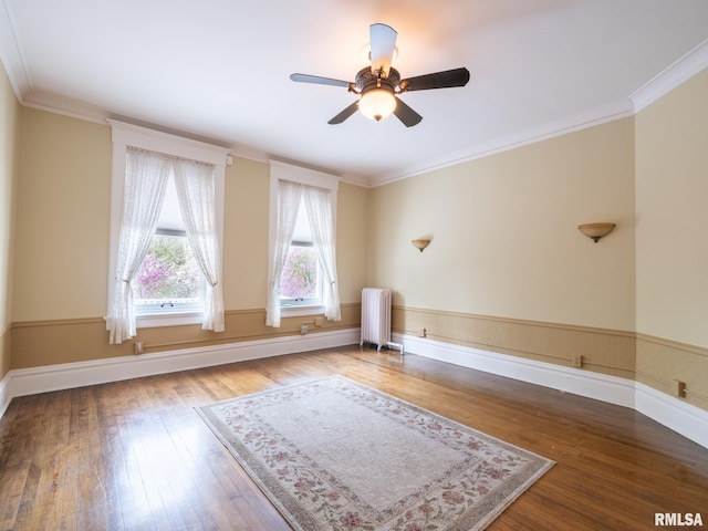 unfurnished room with crown molding, a ceiling fan, radiator heating unit, and wood finished floors