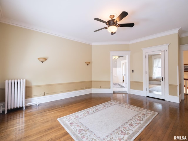 empty room with ceiling fan, crown molding, baseboards, radiator heating unit, and hardwood / wood-style floors