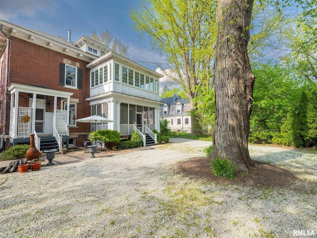 back of property featuring a sunroom and brick siding
