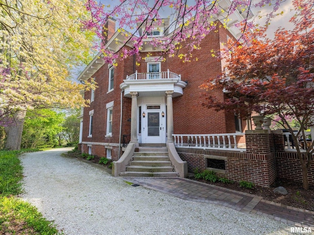 view of front of house featuring a balcony and brick siding