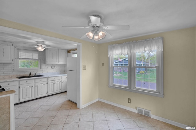 kitchen with light countertops, freestanding refrigerator, a ceiling fan, tasteful backsplash, and visible vents