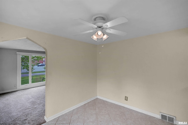 spare room with ceiling fan, arched walkways, baseboards, light tile patterned floors, and visible vents