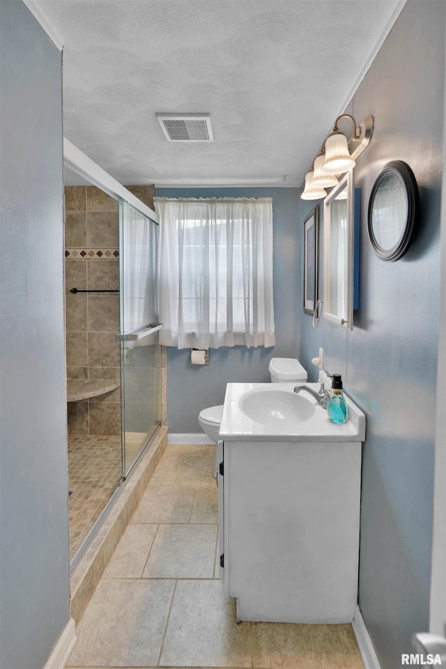 bathroom with visible vents, a shower stall, vanity, baseboards, and toilet