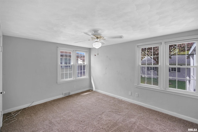 carpeted spare room featuring a ceiling fan, baseboards, and visible vents