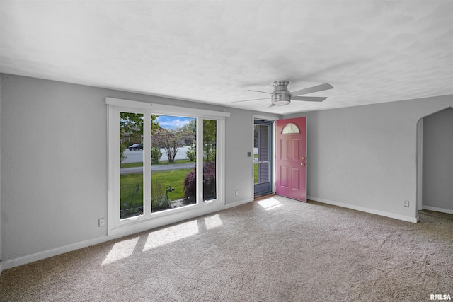 interior space with baseboards, a ceiling fan, and arched walkways