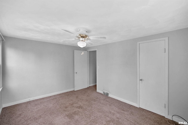 carpeted empty room featuring visible vents, baseboards, and ceiling fan