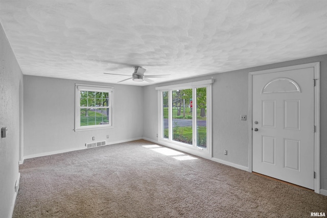unfurnished living room featuring carpet, a ceiling fan, a textured ceiling, and visible vents