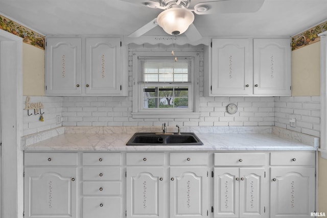 kitchen with a sink, decorative backsplash, a ceiling fan, and white cabinets