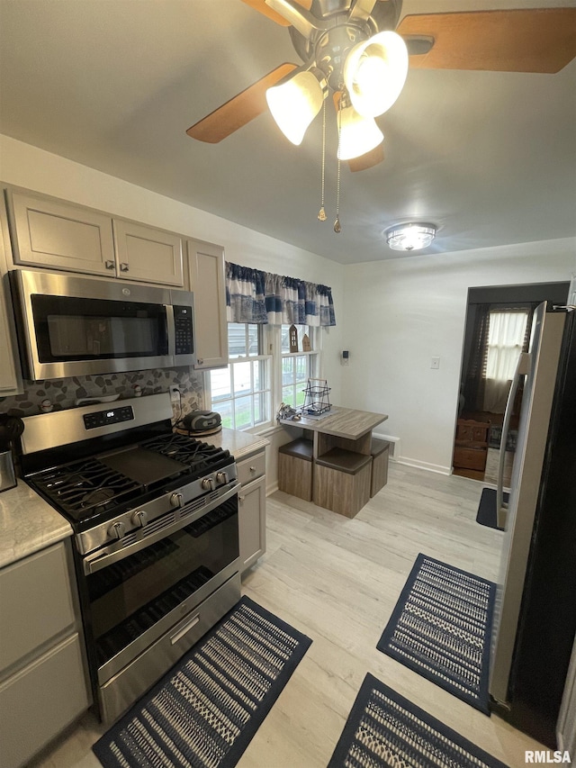 kitchen with ceiling fan, light countertops, gray cabinets, light wood finished floors, and appliances with stainless steel finishes