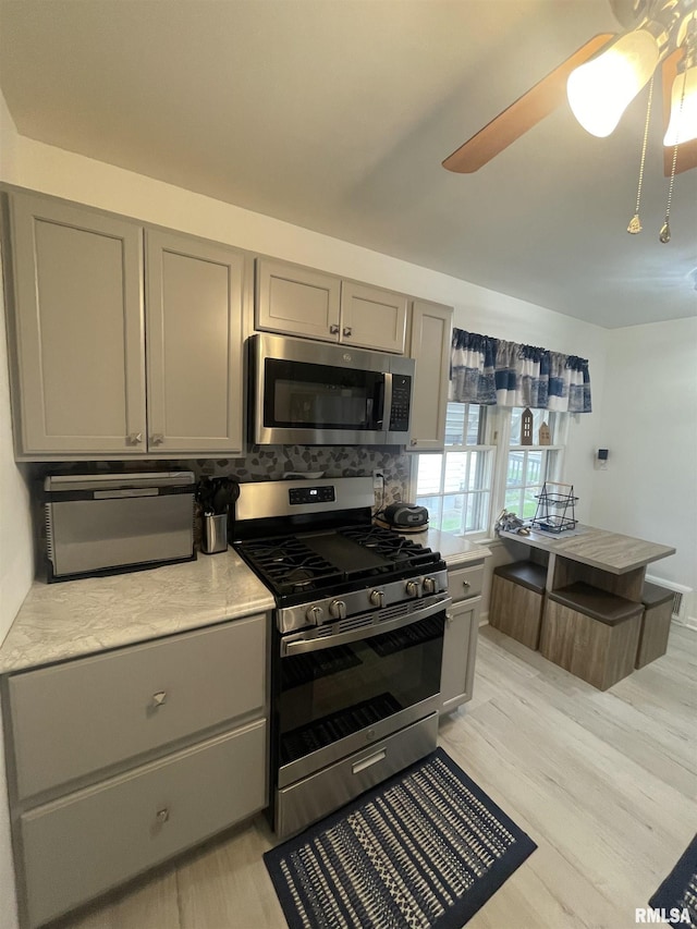 kitchen featuring gray cabinets, a ceiling fan, appliances with stainless steel finishes, light countertops, and light wood finished floors