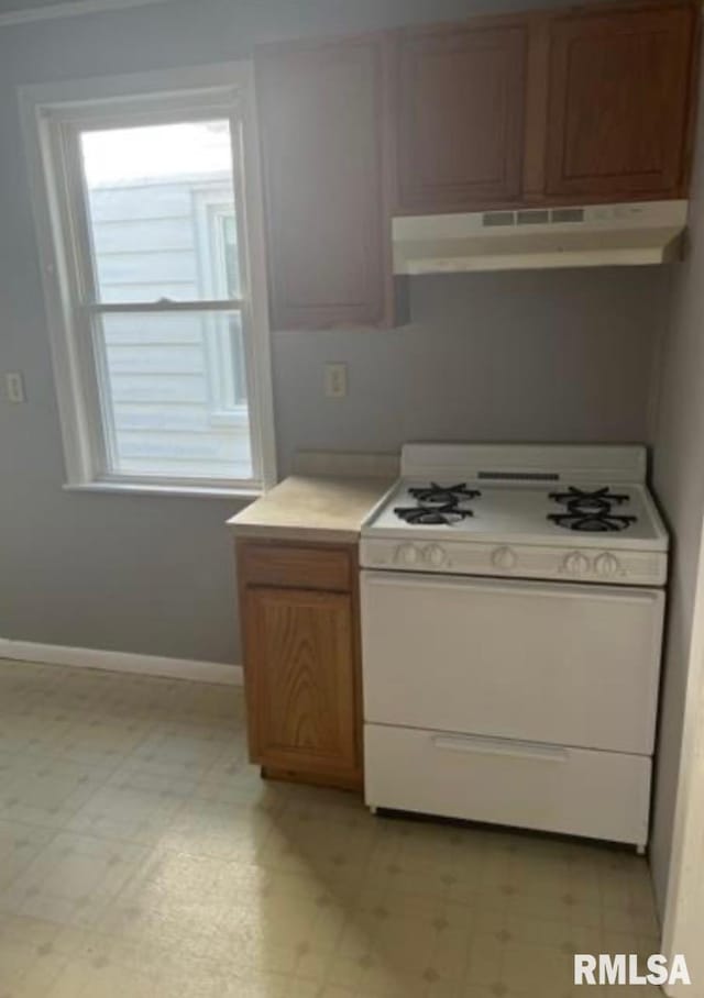 kitchen featuring light countertops, light floors, white gas range oven, and under cabinet range hood