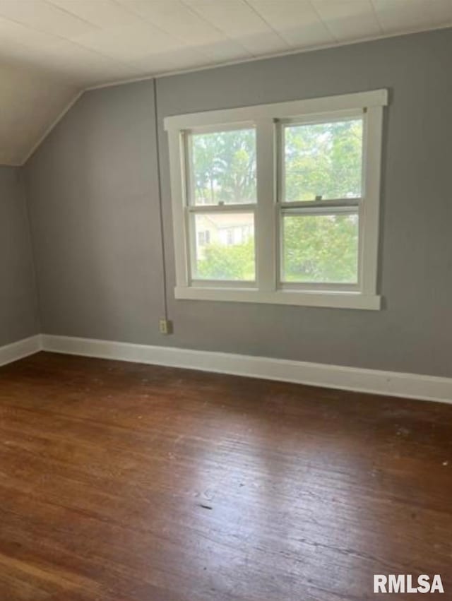 additional living space featuring baseboards, dark wood finished floors, and lofted ceiling