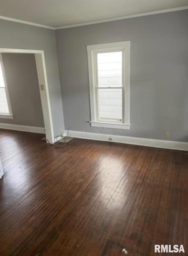 spare room with crown molding, baseboards, and dark wood finished floors